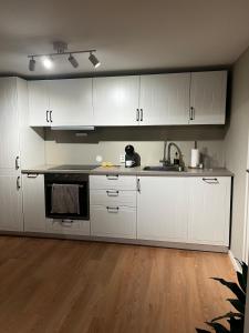 a kitchen with white cabinets and a sink at Apartment right by Karmsund in Karmøy