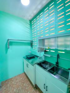een blauwe keuken met een wastafel en een fornuis bij Luigi Guest House & Kitchen in Sattahip