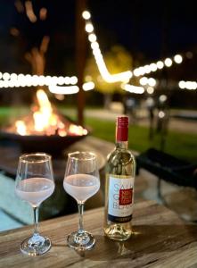 a bottle of wine and two glasses on a table at Badash Tiny Village - Tiny Houses with Heated Pool & BBQ in Polovragi