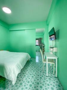een groene kamer met een bed en een bureau bij Luigi Guest House & Kitchen in Sattahip