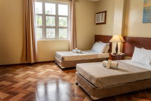 a hotel room with two beds and a window at Lenma Family Inn in Davao City