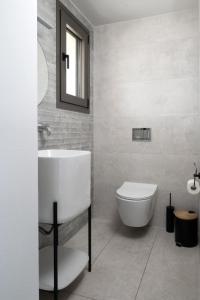 a white bathroom with a sink and a toilet at Aetheria Luxury Villa in Kalithies