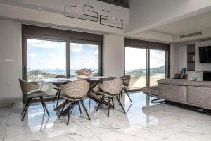 a dining room with a table and chairs and a couch at Aetheria Luxury Villa in Kalithies