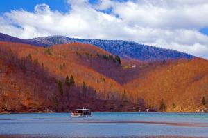 a boat on a lake in front of a mountain at Guesthouse Zafran in Smoljanac
