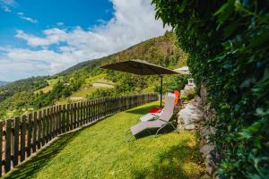 a chair and an umbrella next to a fence at Maso Fallmerayer - Fallmerayerhof in Albes