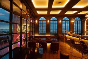 a restaurant with tables and chairs in a room with windows at Grand Tara Garden Thai Hotel in Bangkok
