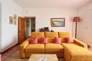 a living room with a yellow couch with pink pillows at Manas Slowliving - Sines in Sines