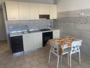 une cuisine avec des armoires blanches et une table avec des chaises dans l'établissement Appartamenti STELLA MARINA- Posto Rosso, à Alliste 21 autres photos