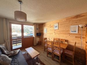 a dining room with a table and a wooden wall at Mottaret - 2 pièces - Pied des pistes avec vue - Parking in Les Allues