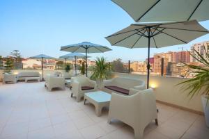 un patio con sedie bianche, tavoli e ombrelloni di alouane rabah a Orano