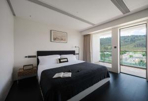 een slaapkamer met een groot bed en een groot raam bij Fuxian Lake Su Qing Qingzhou Cliff Hotel in Luju +96 foto's