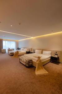 タンジェにあるSuites By Le Rêveのベッド2台とソファが備わる広いホテルルームです。