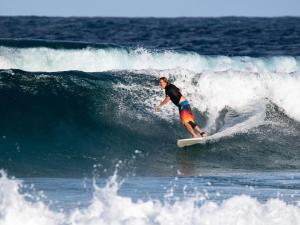 a man riding a wave on a surfboard in the ocean at Turtle Cove Self-Catering Lodge & Yoga Shala in Praia do Tofo
