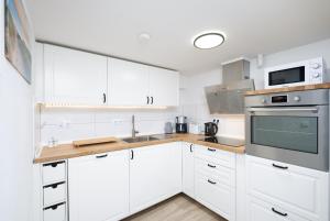 a white kitchen with white cabinets and a microwave at Gästehaus "Kleines Stadtidyll" -Zimmer und Apartments in Geesthacht +10 photos
