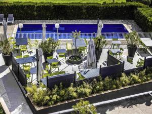 Un patio con sillas y mesas y una piscina. en ibis Styles Chalon sur Saône, en Chalon-sur-Saône