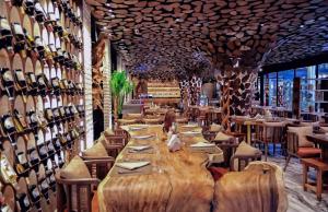 a restaurant with a large wooden table and chairs and wine bottles at Shkoder Grand Hotel Europa, Affiliated by Melia in Shkodër