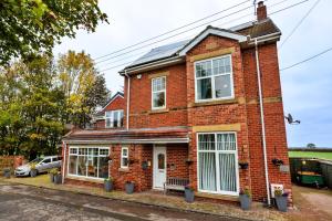 ein rotes Backsteinhaus mit Fenstern auf einer Straße in der Unterkunft Finest Retreats - The Storehouse in Choppington