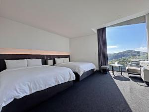 a hotel room with two beds and a large window at Hotel ORA Incheon in Incheon