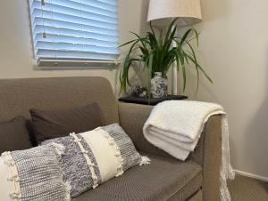 a couch with a pillow and a plant on a table at Jacaranda House Garden Suite in Brisbane