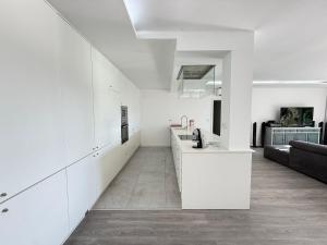 a white kitchen with a counter and a living room at Villa Teixugueiras 1 - Gerês in Vieira do Minho