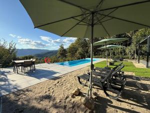 a couple of chairs and an umbrella next to a pool at Villa Teixugueiras 1 - Gerês in Vieira do Minho