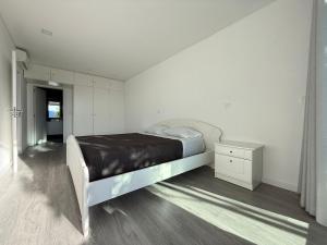 a white bedroom with a bed and a night stand at Villa Teixugueiras 1 - Gerês in Vieira do Minho +38 photos