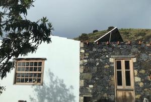 a building with two windows and a rock wall at Casa La Tedera in El Pinar del Hierro