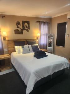 a bedroom with a large white bed with two pictures on the wall at Anique's Self Catering in Beaufort West