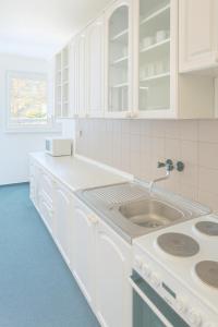 a kitchen with white cabinets and a sink at Apartmány MONTARA in Donovaly