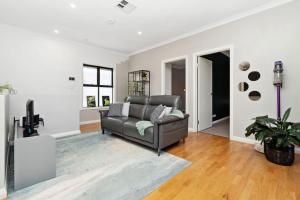 Una sala de estar con un sofá y un televisor. en Bright 2-Bed Townhouse with Balcony & Garage, en Woodville South