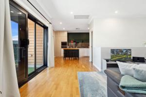 Una sala de estar con un sofá y una cocina. en Bright 2-Bed Townhouse with Balcony & Garage, en Woodville South 4 fotos más