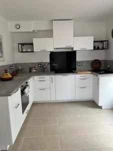 a kitchen with white cabinets and a tile floor at La casemate in LʼIsle-sur-la-Sorgue
