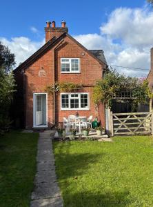 a brick house with a white door and a fence at Delightful 3-bedroom Cottage, Brockenhurst in Brockenhurst