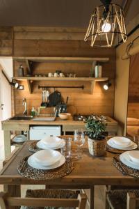 a kitchen with a wooden table with plates and wine glasses at Glamping Poggio Nardini in Montelupo Fiorentino