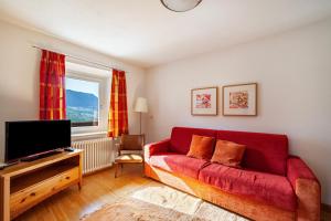 a living room with a red couch and a tv at Gasserhof Ferienwohnung Gravenstein in Caines