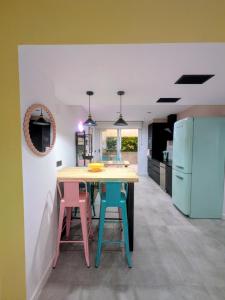 a kitchen with a wooden table and four colorful stools at El Taller de San Martín in Águilas