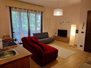 a living room with a red chair and a couch at B&b La Lucciola in Salsomaggiore Terme
