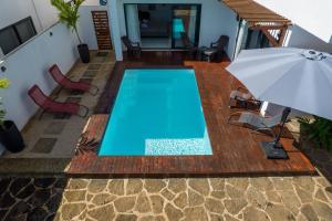 an empty swimming pool with an umbrella and chairs at Maurentvilla in Pointe aux Piments