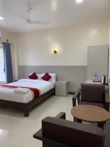 索拉哈Tiffin Home and Restaurant的一间卧室，里面有一张床、一张桌子和一把椅子