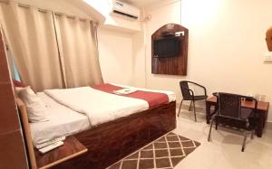 a small bedroom with a bed and a table and chair at Prince Lodge and Banquet in Khairāni