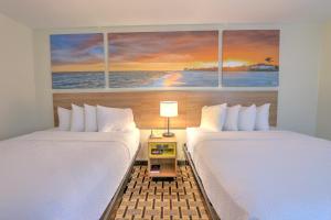 two beds in a room with a painting of the ocean at Hotel Carolina Double Room - 2 Queen Beds in Hilton Head Island
