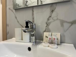 Un lavabo de baño con grifo y cepillos de dientes. en Welc-ōM Celeste Rooms, en Ponte di Brenta