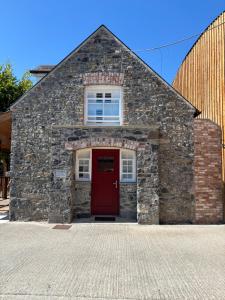 a stone building with a red door on a street at Kells Yard in Feevaghmore