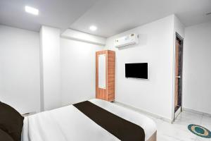 BhathaにあるSuper Hotel O Sneh Rashmi Botanical Garden Surat Formerly Stadium Plazaのベッドと壁にテレビが掛かった寝室