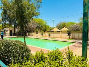 a swimming pool in a park with trees and bushes at Cozy and Stylish 2 Bedroom Retreat in Gaborone in Gaborone