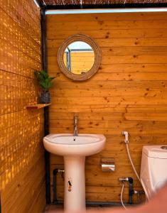 a bathroom with a sink and a mirror on a wooden wall at Night Stars Camp in Bidiyah