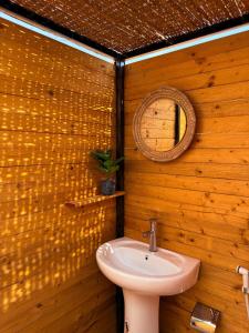 a bathroom with a sink and a mirror on a wooden wall at Night Stars Camp in Bidiyah