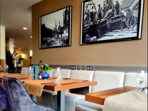 アントワープにあるNovotel Antwerpen - Ekerenの木製のテーブルと白い椅子のあるダイニングルーム