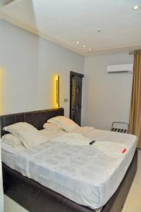 a bedroom with a large bed with white sheets at Triple Tee Luxury Hotel & Service Apartments Surulere in Lagos