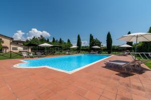 a swimming pool with chairs and an umbrella at Appartamento Mulino in Laterina